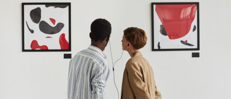 two people looking at art in a gallery with headphones